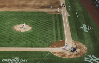 An aerial view of a baseball game in action, featuring a pitcher on the mound mid-throw to a batter at home plate. The catcher and umpire are positioned behind the batter, awaiting the pitch, while infielders are ready for the play. The field is lush and green, marked by dirt paths around the bases, and the field markings indicate 'Opening Day'.