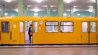 a person standing next to a yellow train
