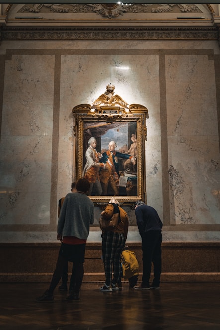 a group of people looking at a painting on a wall