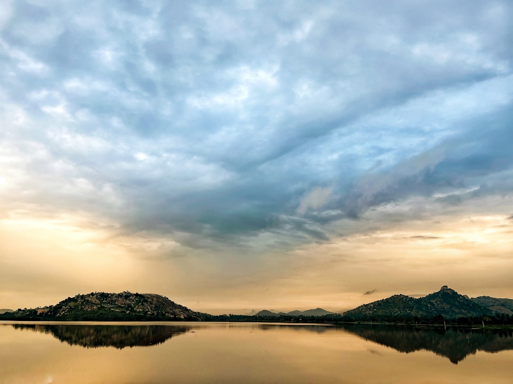 a body of water with trees and hills in the background