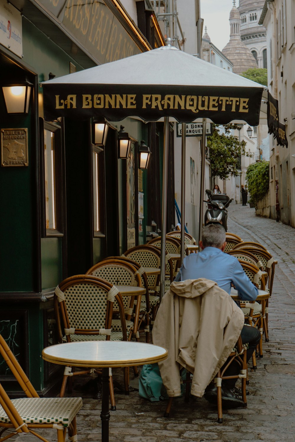 a person sitting at a table outside a restaurant