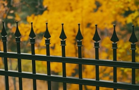 a group of black and gold fence posts with a yellow and orange background
