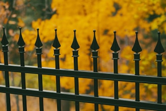 a group of black and gold fence posts with a yellow and orange background