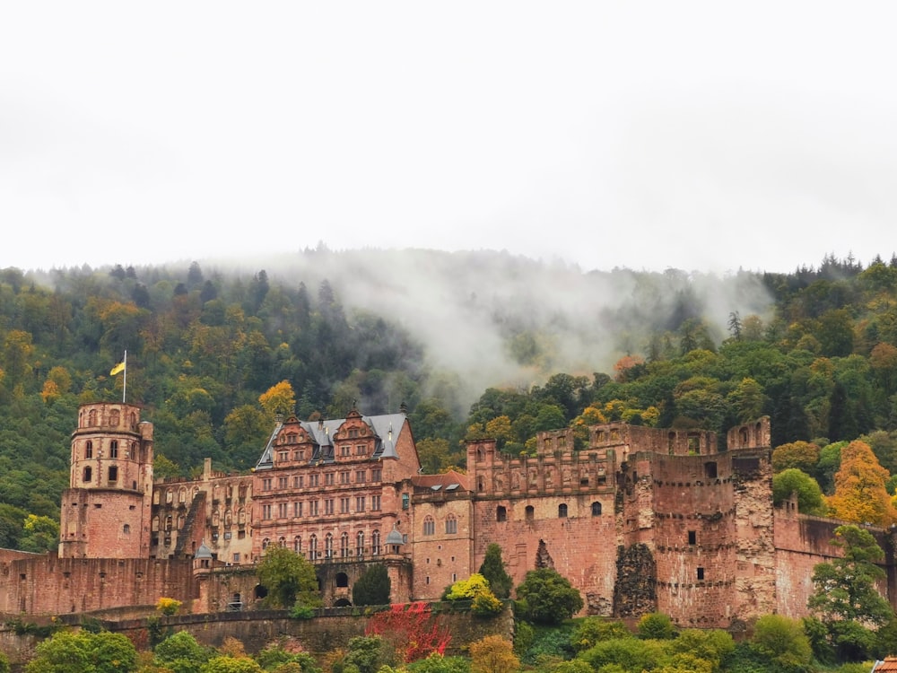 a castle on a hill with trees and a cloud of smoke