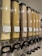 A row of transparent dispensers filled with various types of grains and pasta. Each dispenser is labeled with pricing information in kr/kg and the type of grain or pasta, such as couscous, bulgur, and macaroni. The dispensers are aligned and well-organized, equipped with black handles at the bottom for dispensing the contents.