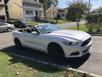 a white sports car parked on a driveway in front of a house