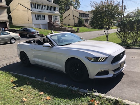 a white sports car parked on a driveway in front of a house