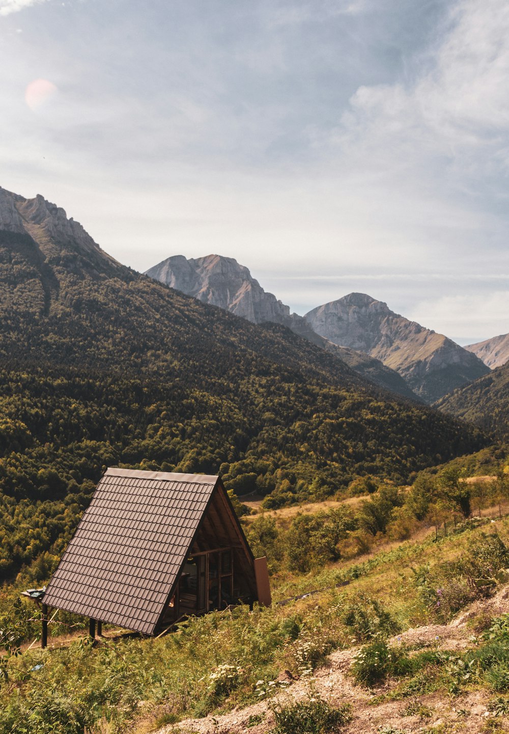 a building in the middle of a valley with mountains in the background