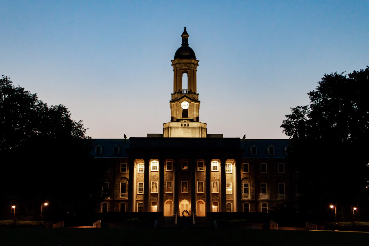 A clock tower building on the Penn State campus in State College, lit up at dusk