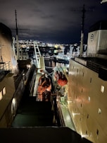 A panoramic view of a busy port managed by Ocean Line Marine at sunset, with ships docked and lights glowing.