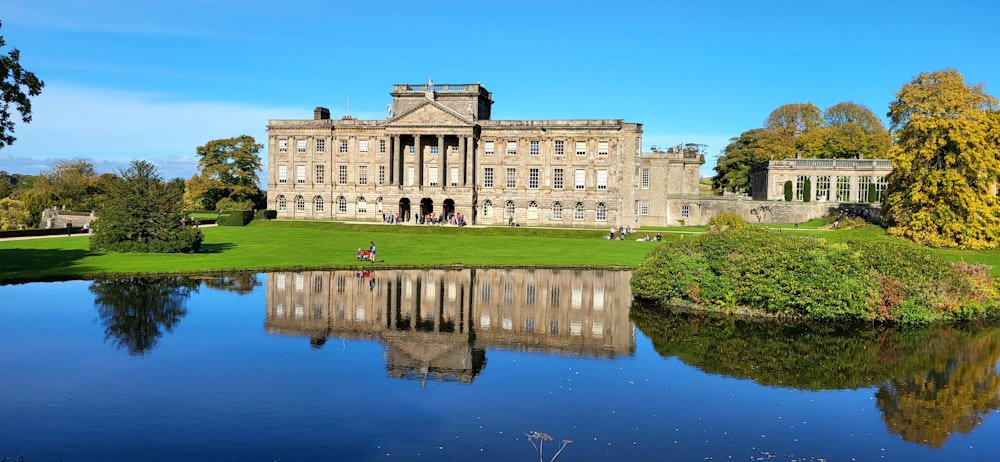 a large building with a pond in front of it with Lyme Park in the background