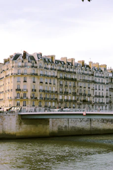 A stunning luxury apartment balcony overlooking the Danube River with Budapest's historic skyline at sunset.