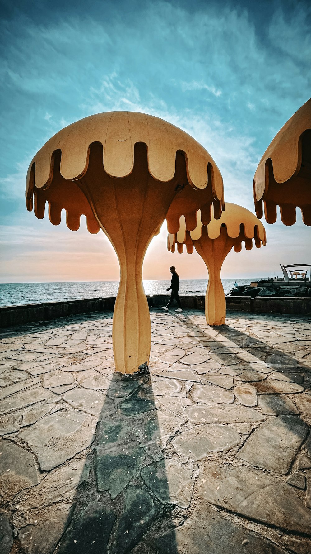 a large sculpture of a person standing on a stone walkway by the water