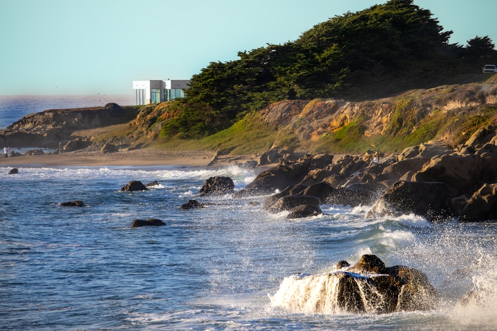 a rocky beach with a building on the hill