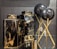 Two black and gold marble-patterned vases are displayed alongside two black spherical objects on golden stands. The vases have a glossy finish, with the marble pattern adding a luxurious touch. The spherical objects appear to be decorative, supported by elegant crisscrossed stands.