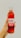 A hand holds a glass bottle labeled 'RAW Kombucha' with hibiscus lime flavoring and the text 'herbal super tea'. The bottle contains a red liquid, and the background is plain and light-colored.