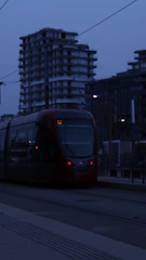 A sleek modern tram gliding through a cityscape at dusk, highlighting advanced rail technology.