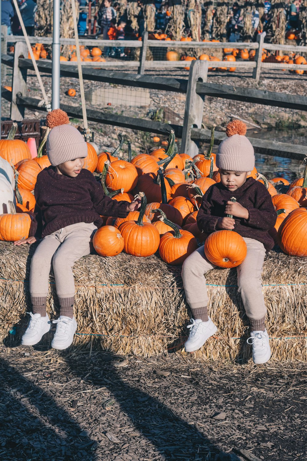 a couple of people sitting on hay next to pumpkins