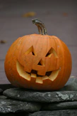 a carved pumpkin on a rock