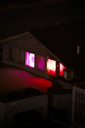 A shadowy rooftop party glowing with red and gold neon lights under a starry night sky.