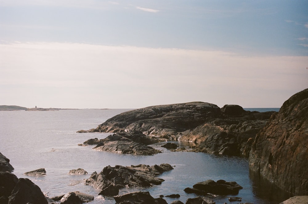 a rocky beach with a body of water in the background