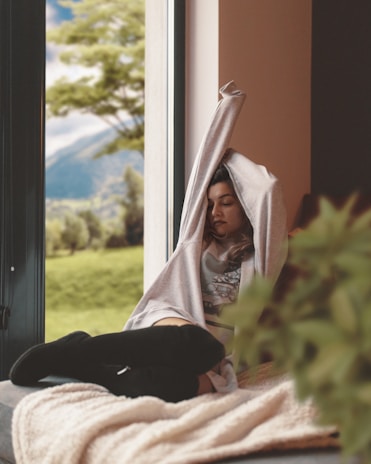 A smiling person stretching by a window, enjoying a moment of calm in a busy day.