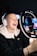 A young content creator smiling while streaming live on a laptop.