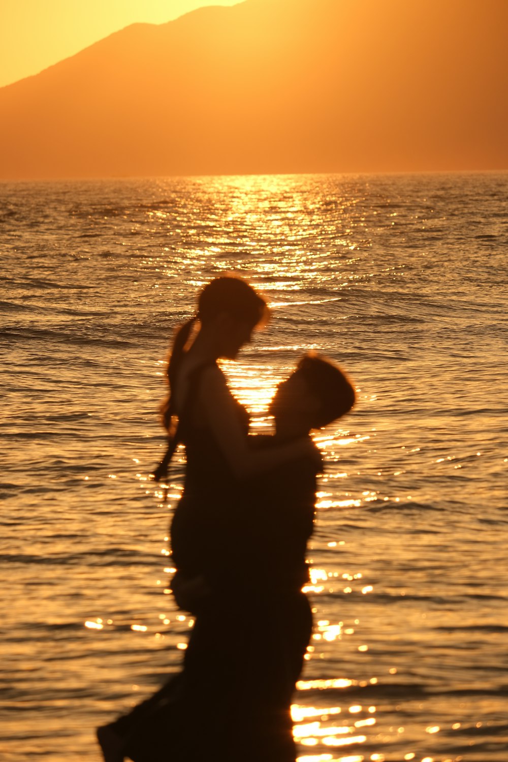 a man and woman holding hands and looking at the water