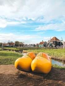 Traditional Dutch wooden shoes next to colorful Colombian woven baskets on a rustic wooden table.