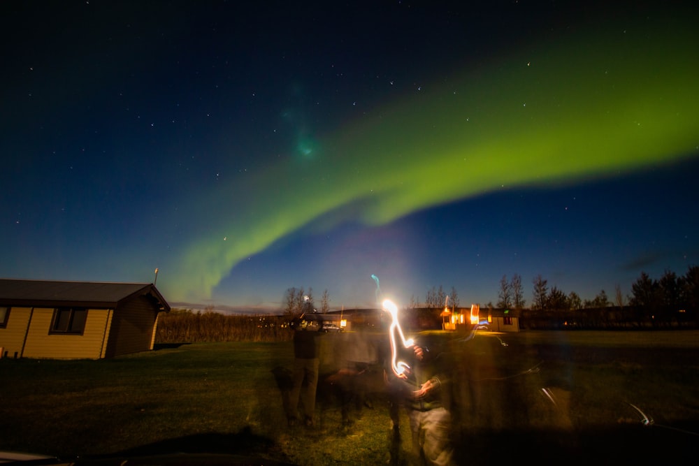 a group of people standing in front of a green aurora in the sky