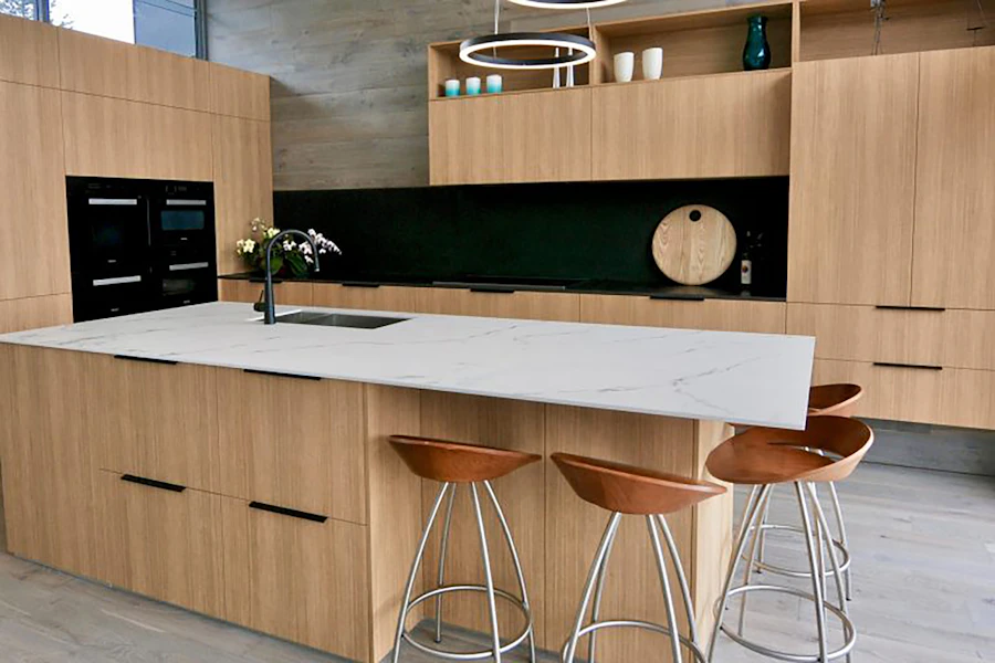 Kitchen with oak cabinetry, a white stone island and copper bar stools