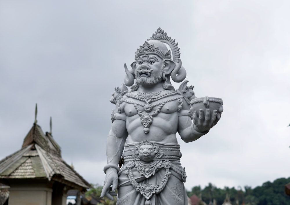 a statue of a person with a crown and a building in the background