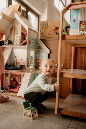 a child sitting on a stool holding a wooden toy