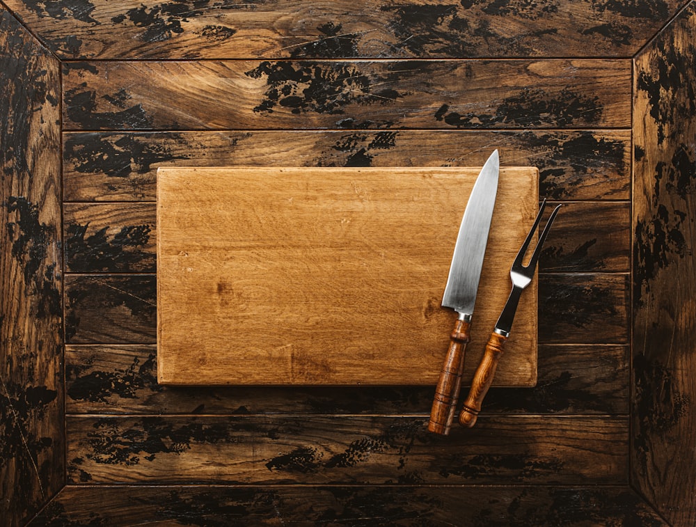 a knife and a board on a wooden surface