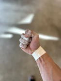 Close-up of a female athlete’s arm with glowing energy aura and chalk dust particles floating.