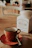 A warm, rustic kitchen scene with a cup of hot panela drink and a small sack of panela blocks on a wooden table.