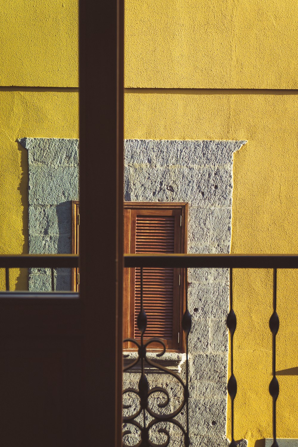 eine gelbe Wand mit einem Fenster und einem Geländer