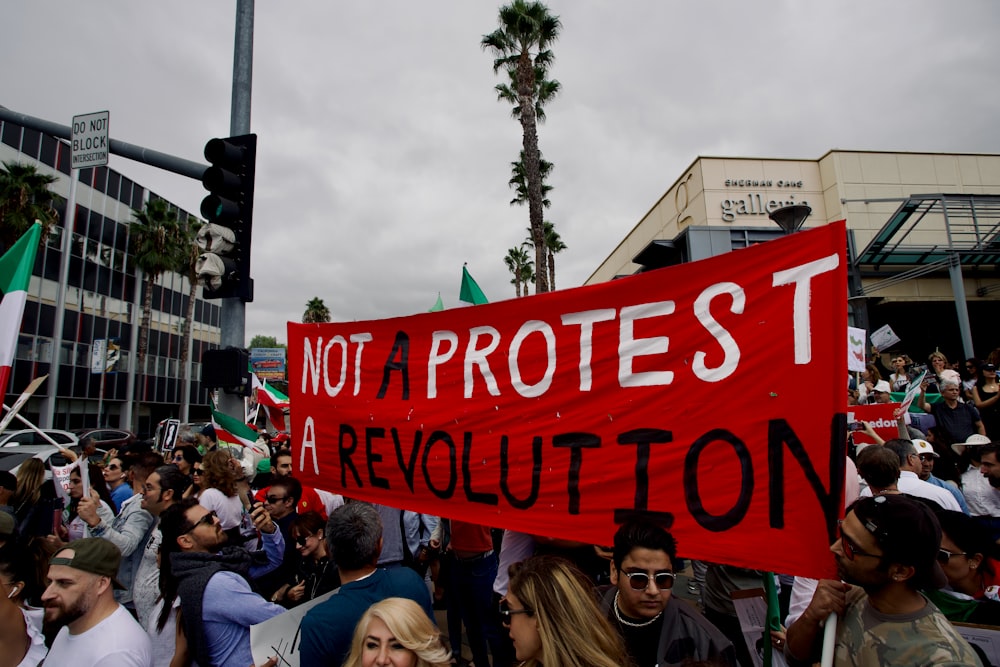 a large crowd of people holding a red sign