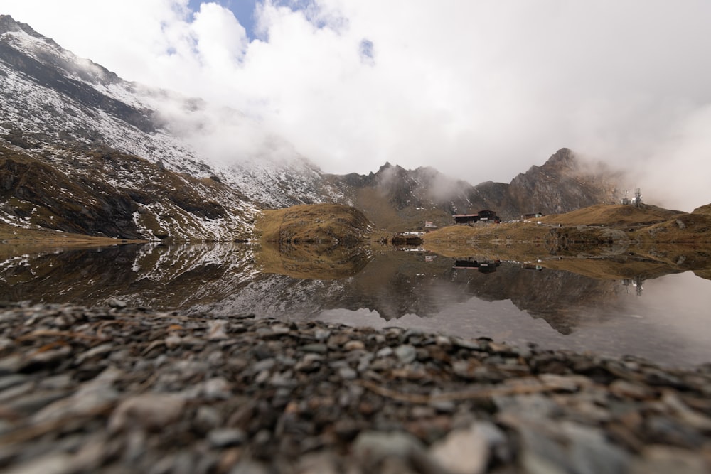 a rocky beach with a body of water and a mountain in the background