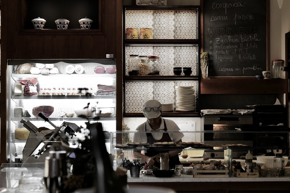 a person in a white mask behind a counter with a menu