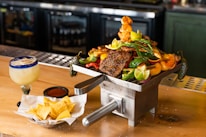 A rustic wooden table set with grilled meats and bowls of chimichurri ready to serve.