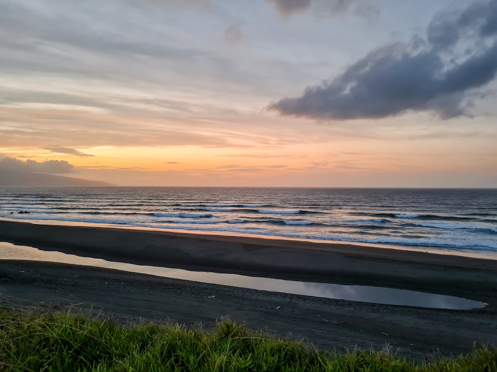 a beach with waves and grass