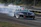 Racing car speeding on a track with smoke trailing from the tires during a drag race event