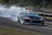 Racing car speeding on a track with smoke trailing from the tires during a drag race event