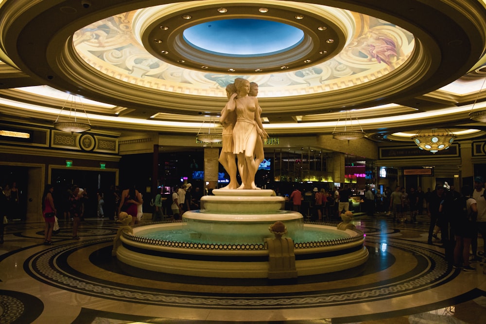 a statue in a large room with people and a large ceiling