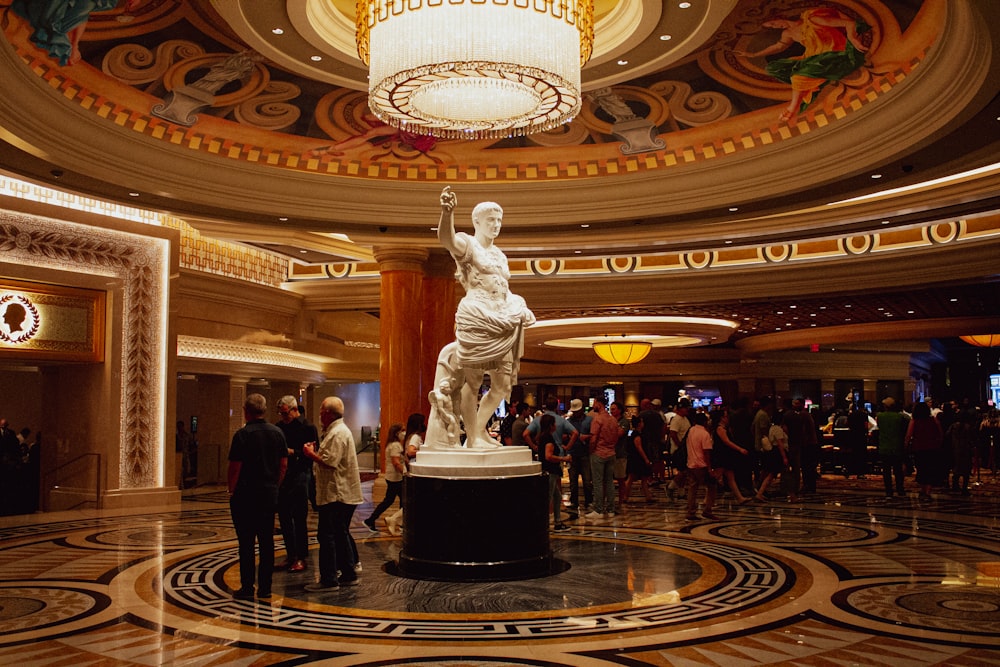 uma grande estátua em uma grande sala com pessoas em pé ao redor