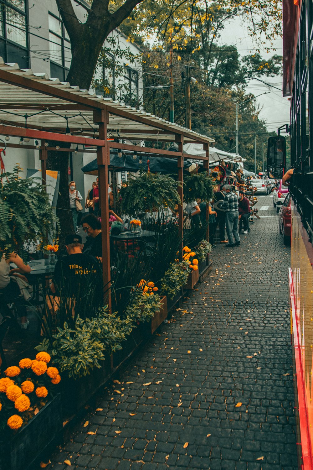 a group of people walking down a sidewalk next to a garden