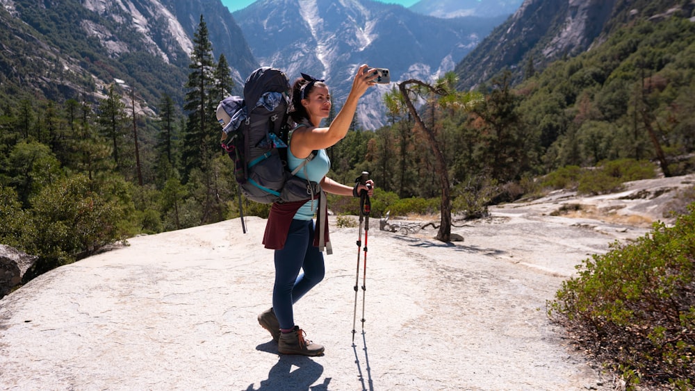 a man with a camera on a trail in the mountains