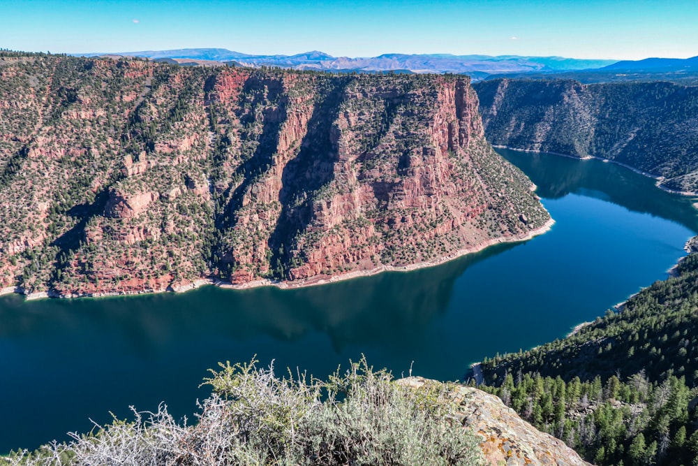a large cliff with a body of water below with Flaming Gorge Reservoir in the background