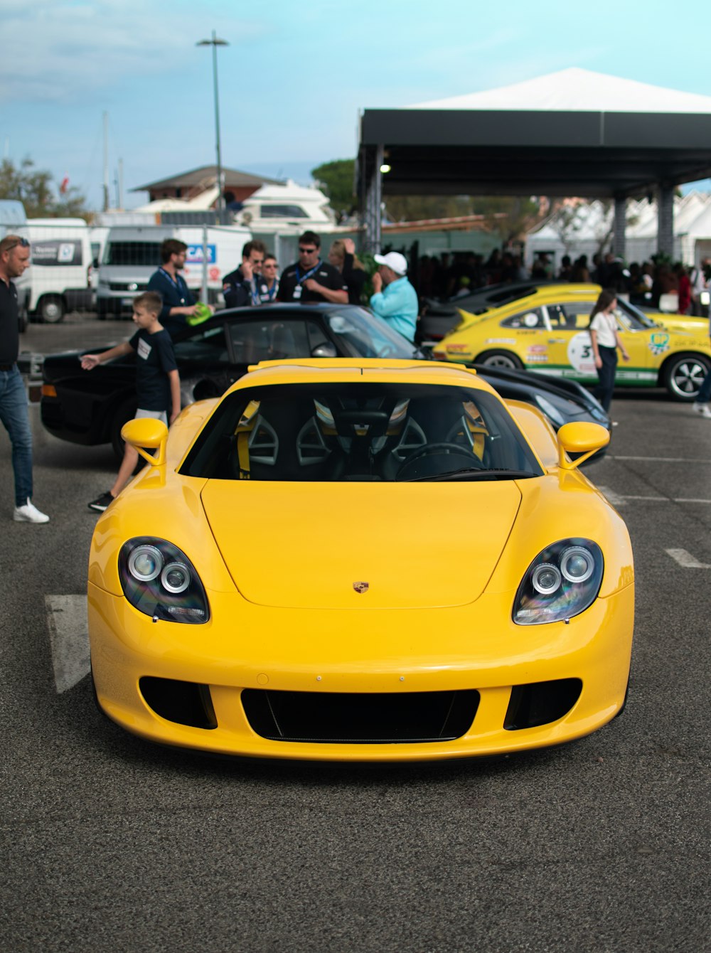a yellow sports car parked in a parking lot with people and cars